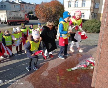 Przedszkolacy wraz z Panią Dyrektor wręczają kwiaty pod pomnikiem 'Ofiarom Wojen i Przemocy'. - powiększ